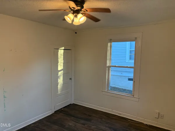 a view of empty room with wooden floor and fan