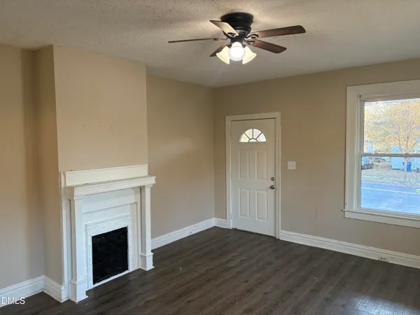 a view of a livingroom with a fireplace a ceiling fan and wooden floor