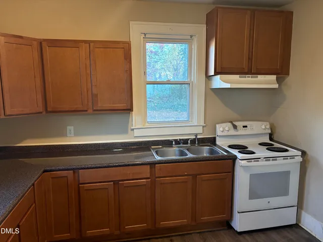 a kitchen with granite countertop cabinets stove and sink
