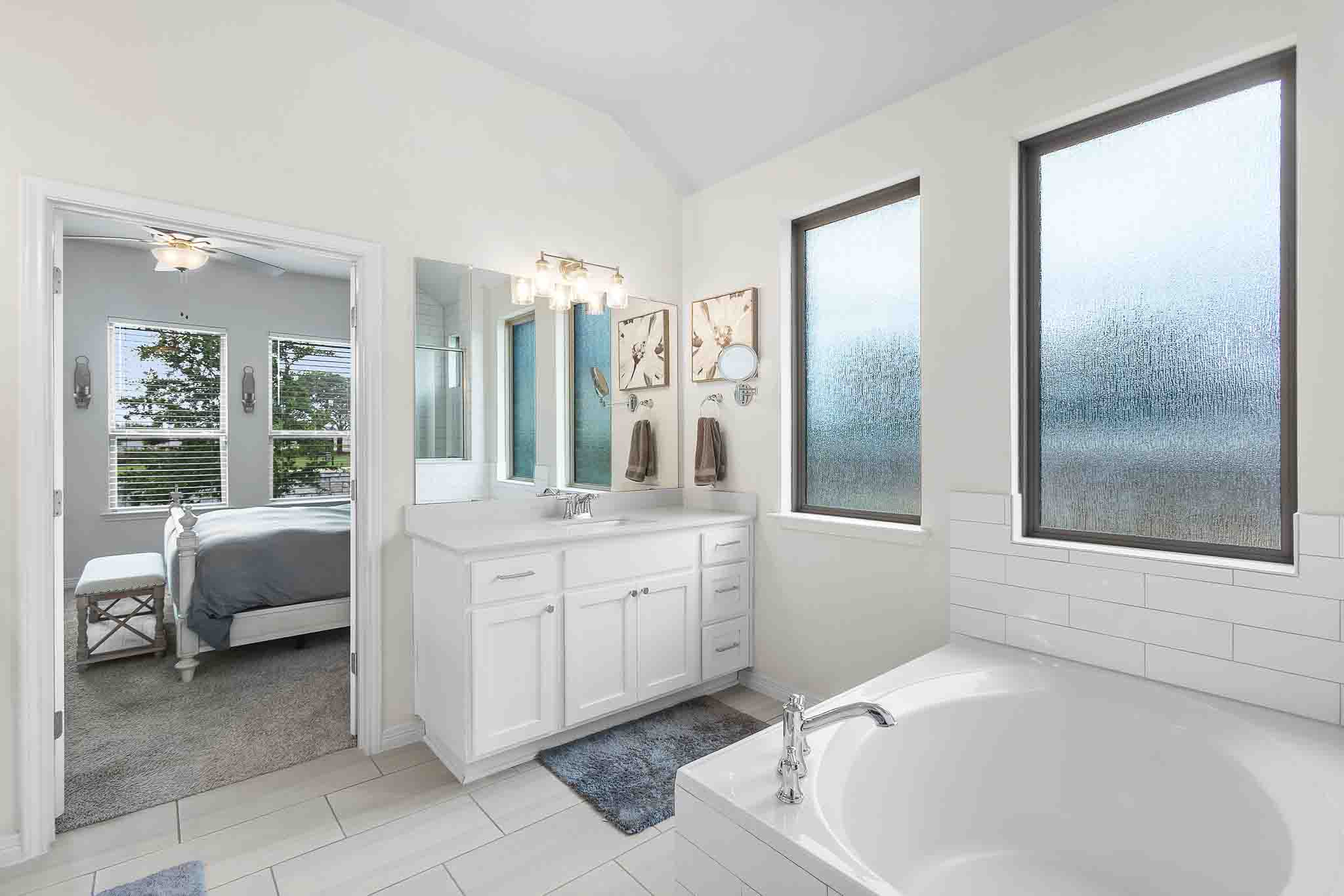 166 West Branch Road Kyle, TX 78640 - Photo 17 of 39 A well-lit primary bathroom provides a private retreat with a spacious soaking tub and an adjoining bedroom.