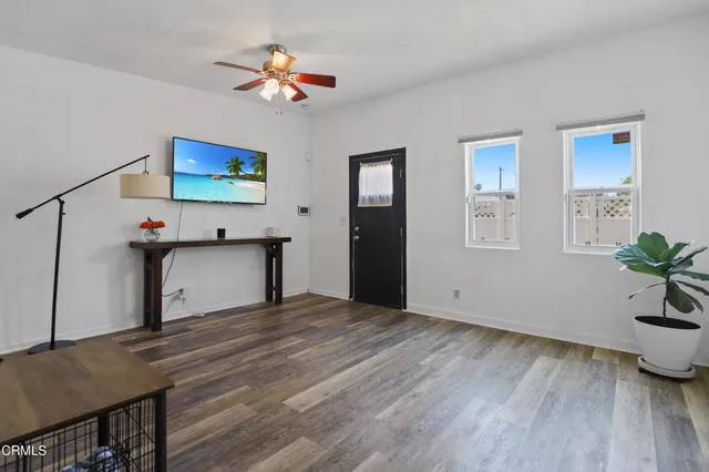 an empty room with wooden floor and ceiling fan