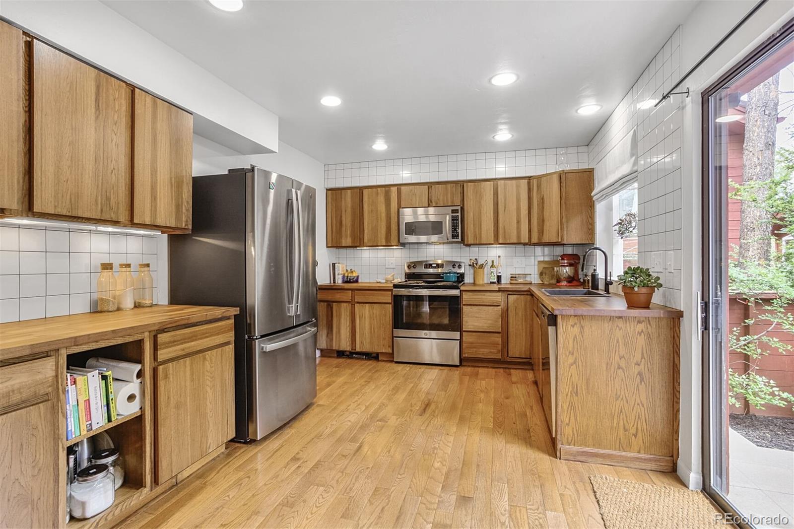 23646 Genesee Village Road Golden, CO 80401 - Photo 6 of 29 a kitchen with kitchen island granite countertop wooden floors stainless steel appliances a sink and a window