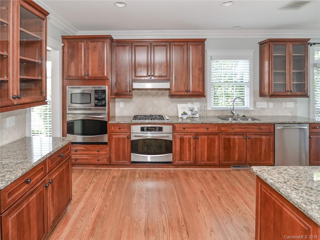 4317 Birkshire Heights Fort Mill, SC 29708 - Photo 11 of 23 a kitchen with stainless steel appliances granite countertop wooden cabinets a sink and dishwasher a stove top oven with wooden floor