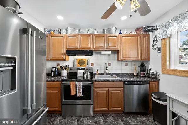 a kitchen with stainless steel appliances granite countertop a refrigerator a sink a stove a microwave and wooden cabinets