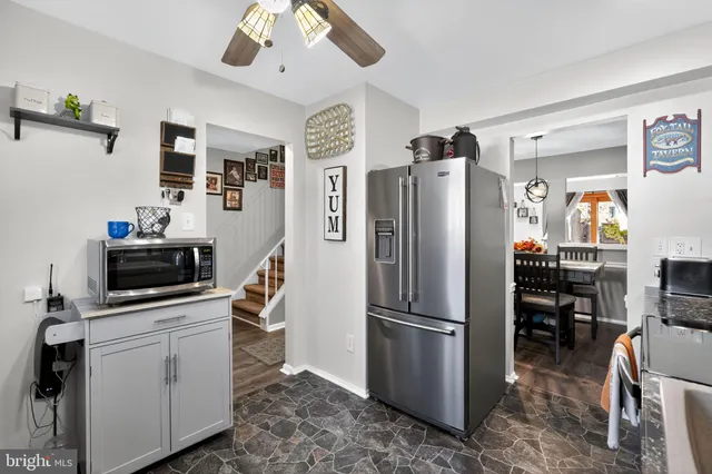 a kitchen with stainless steel appliances a refrigerator a stove a sink a dining table and chairs with wooden floor