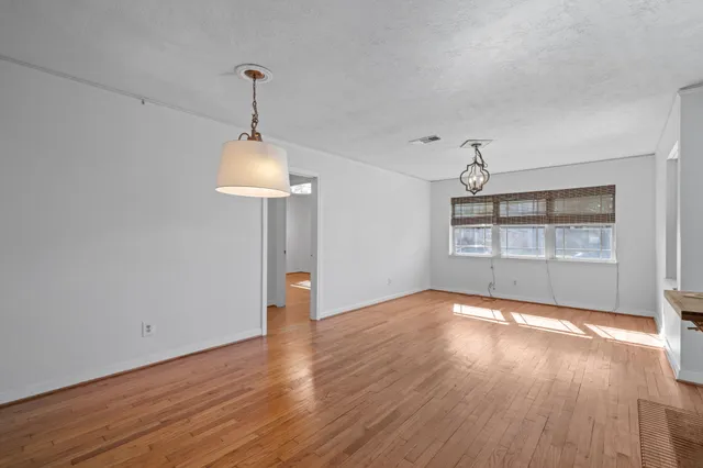 a view of an empty room with window and wooden floor