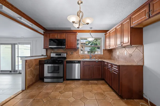 a kitchen with stainless steel appliances granite countertop a stove top oven a sink dishwasher a dining table and chairs with wooden floor