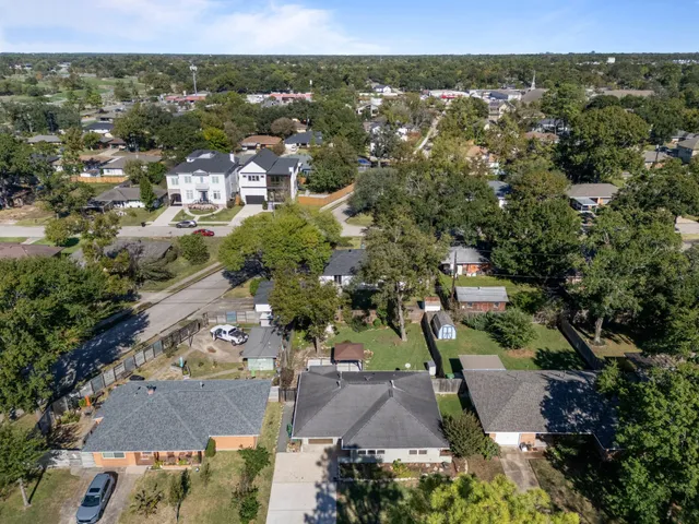 an aerial view of residential houses with outdoor space and trees