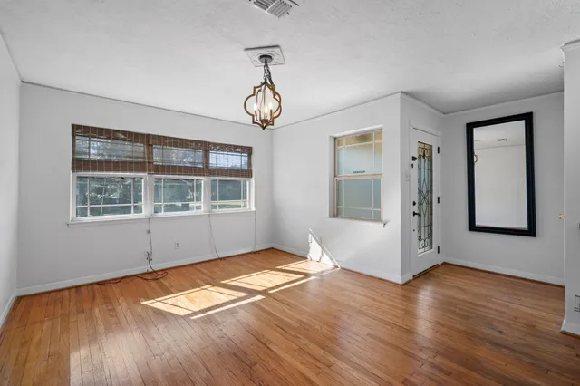 a view of an empty room with wooden floor and windows