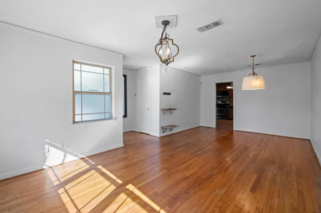 an empty room with wooden floor mirror and windows