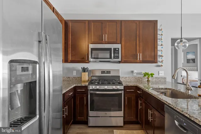 a kitchen with stainless steel appliances granite countertop a stove top oven a sink dishwasher a dining table and chairs with wooden floor