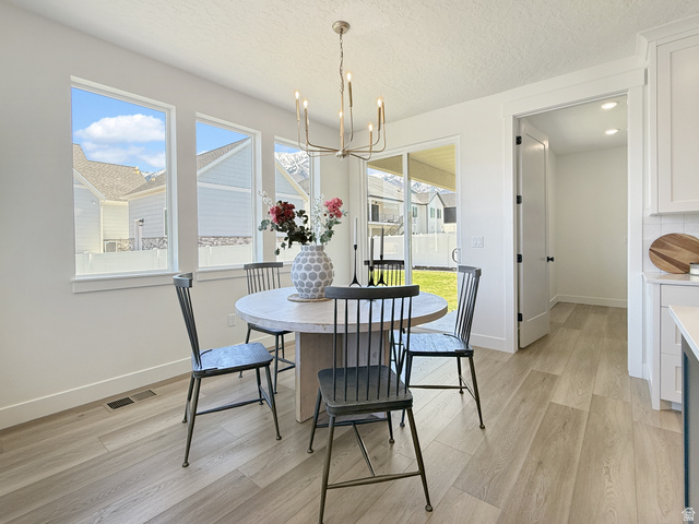 916 Rocky Mountain Way Elk Ridge, UT 84651 - Photo 17 of 54 Dining room featuring light wood-style flooring, suspended lighting, healthy amount of natural light, and a textured ceiling