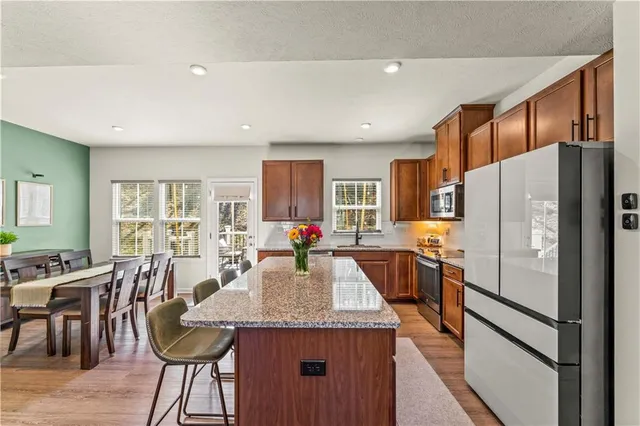 a kitchen with stainless steel appliances granite countertop a kitchen island a stove a refrigerator a table and chairs