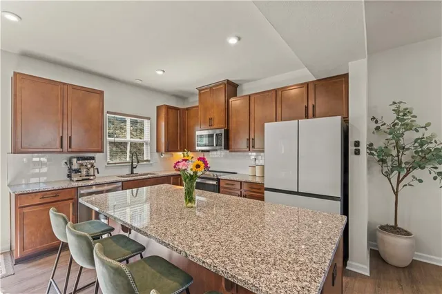 a kitchen with stainless steel appliances granite countertop a refrigerator sink and white cabinets