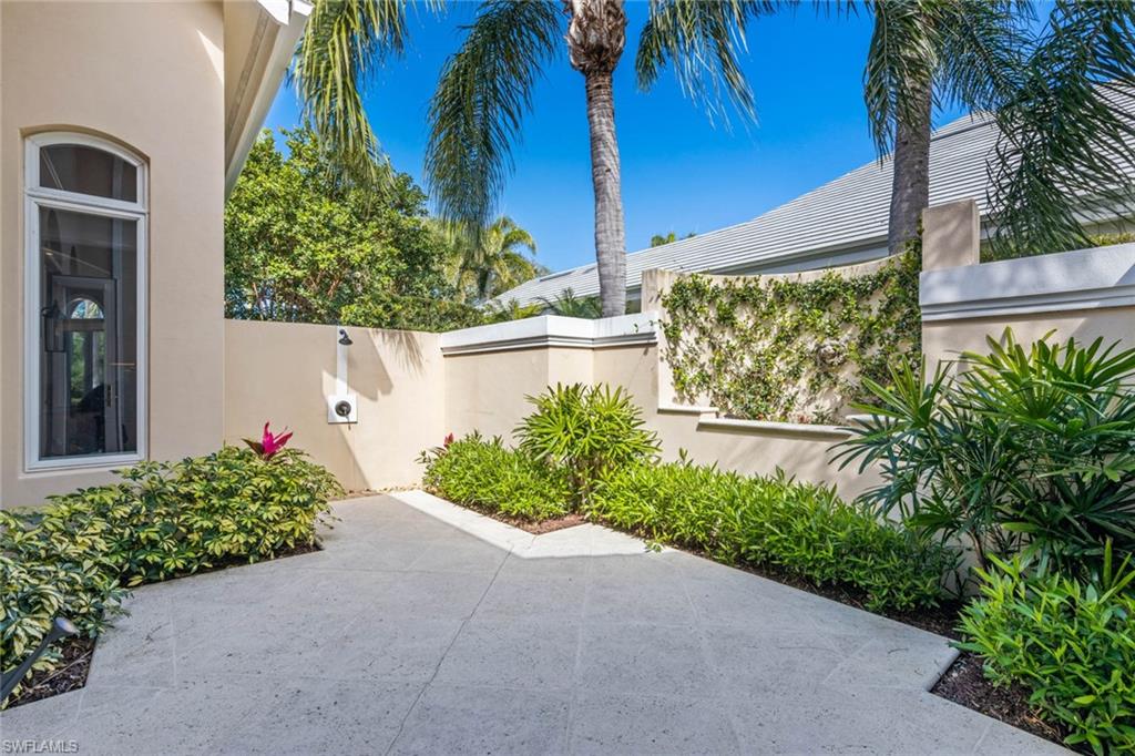 6963 Verde Way Naples, FL 34108 - Photo 20 of 31 a flower garden is sitting in front of a house