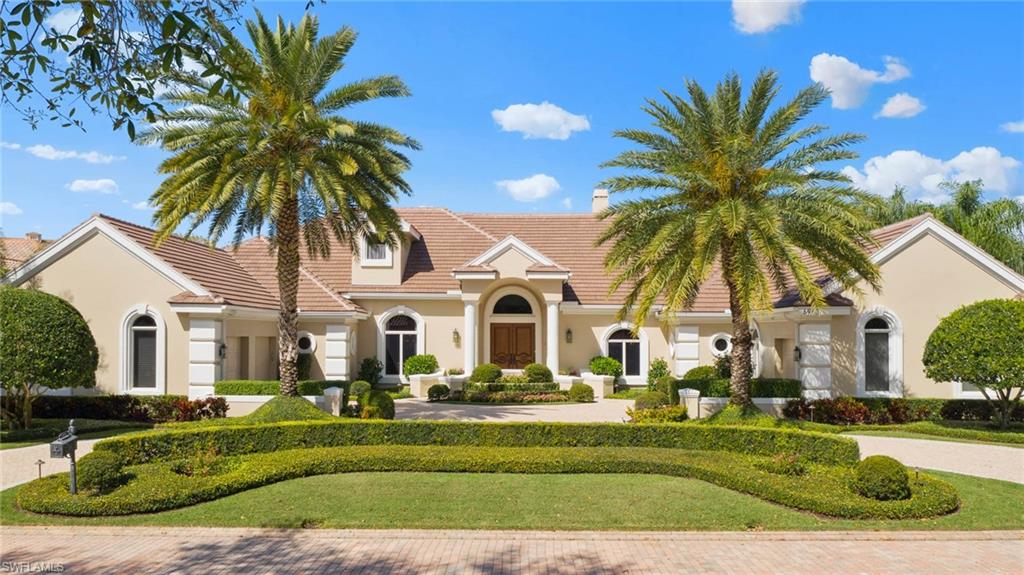 6963 Verde Way Naples, FL 34108 - Photo 2 of 31 a front view of a house with a garden and swimming pool
