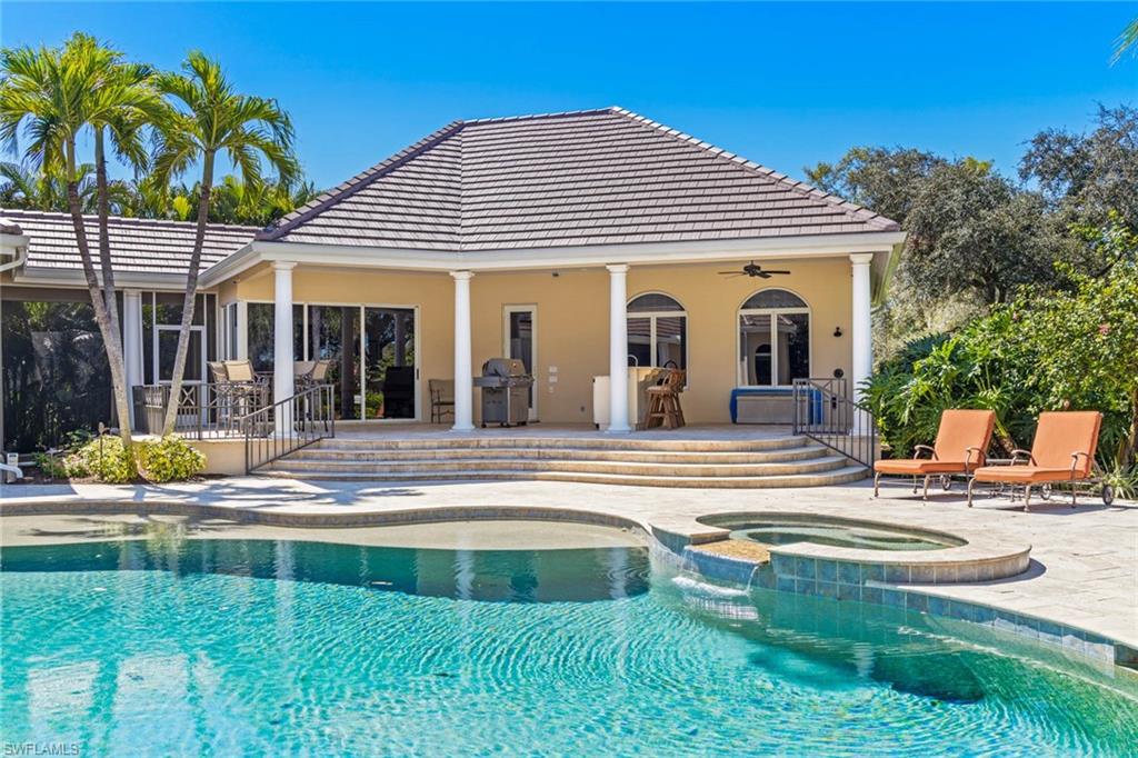 6963 Verde Way Naples, FL 34108 - Photo 25 of 31 a view of a white house with swimming pool lawn chairs and a small yard