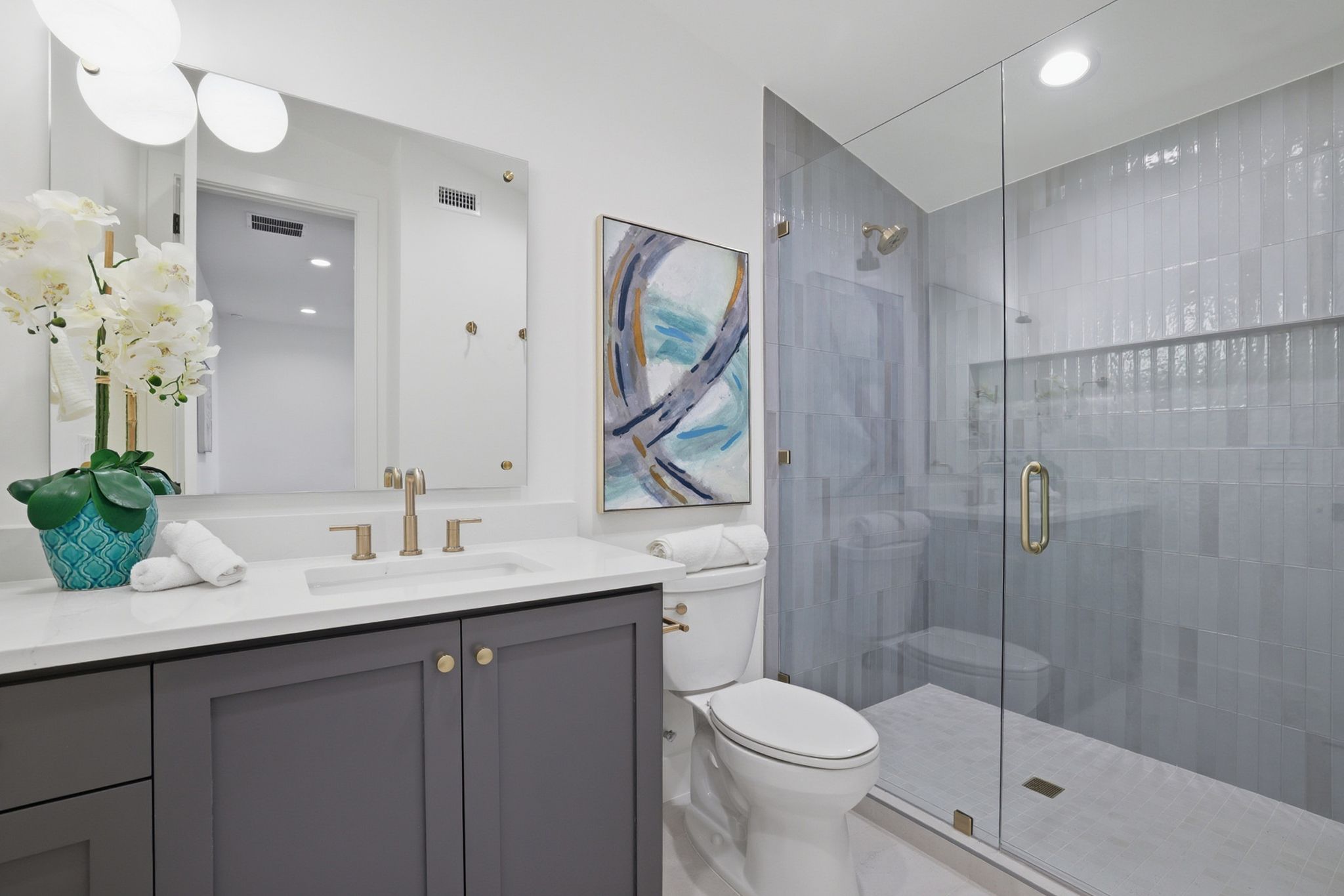 6611 Lexington Road Austin, TX 78757 - Photo 31 of 37 Contemporary bathroom featuring a frameless glass shower enclosure, a full vanity with a white countertop and gray cabinetry, a rectangular undermount sink, and brushed gold fixtures
