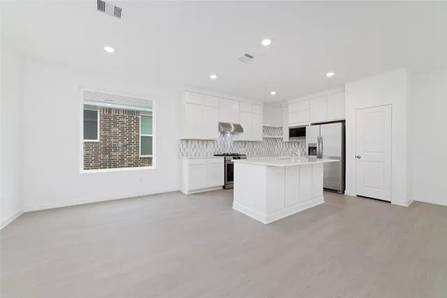 a view of kitchen with kitchen island white cabinets and stainless steel appliances