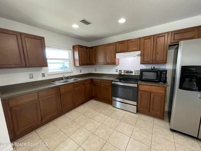 a kitchen with granite countertop a sink stainless steel appliances and cabinets