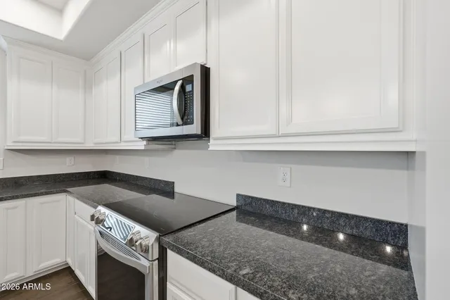 a kitchen with granite countertop white cabinets and stainless steel appliances
