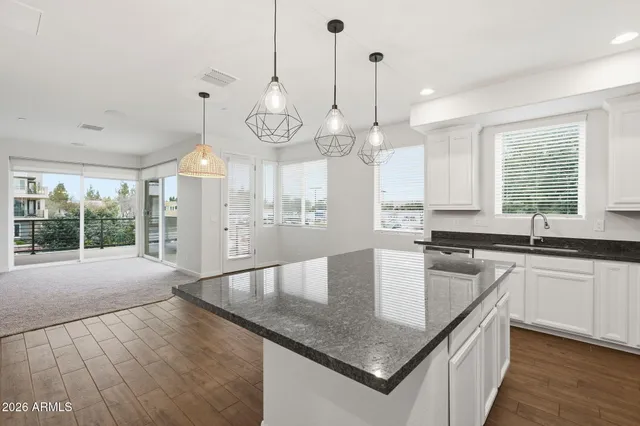 a kitchen with stainless steel appliances granite countertop a sink a stove and a wooden floors