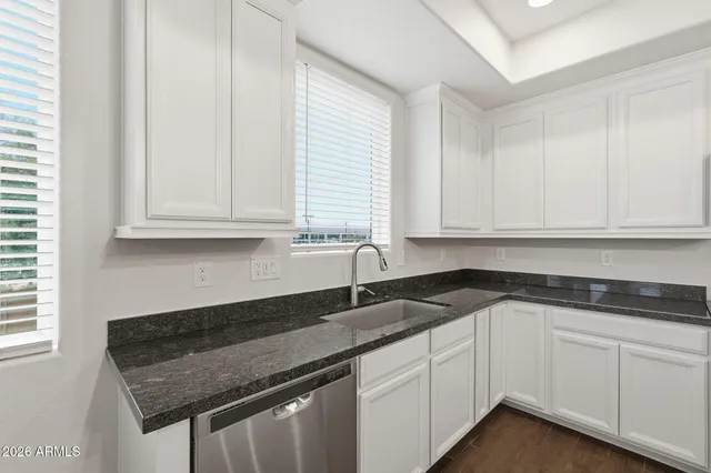 a kitchen with granite countertop white cabinets and a sink