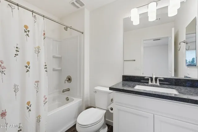 a bathroom with a granite countertop sink a toilet a mirror a bathtub and shower