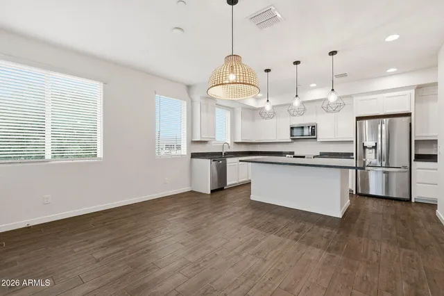 a large kitchen with stainless steel appliances kitchen island granite countertop a stove a sink dishwasher and a refrigerator