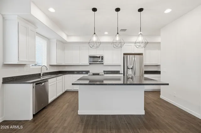 a kitchen with stainless steel appliances granite countertop a sink a stove and a wooden floors