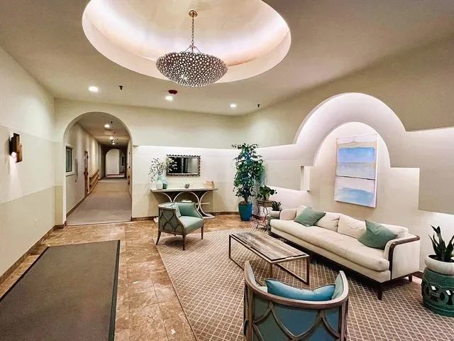 a living room with furniture a chandelier and a large window