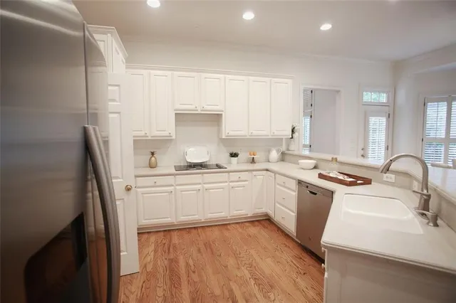 a kitchen with granite countertop white cabinets a sink dishwasher and a stove with wooden floor