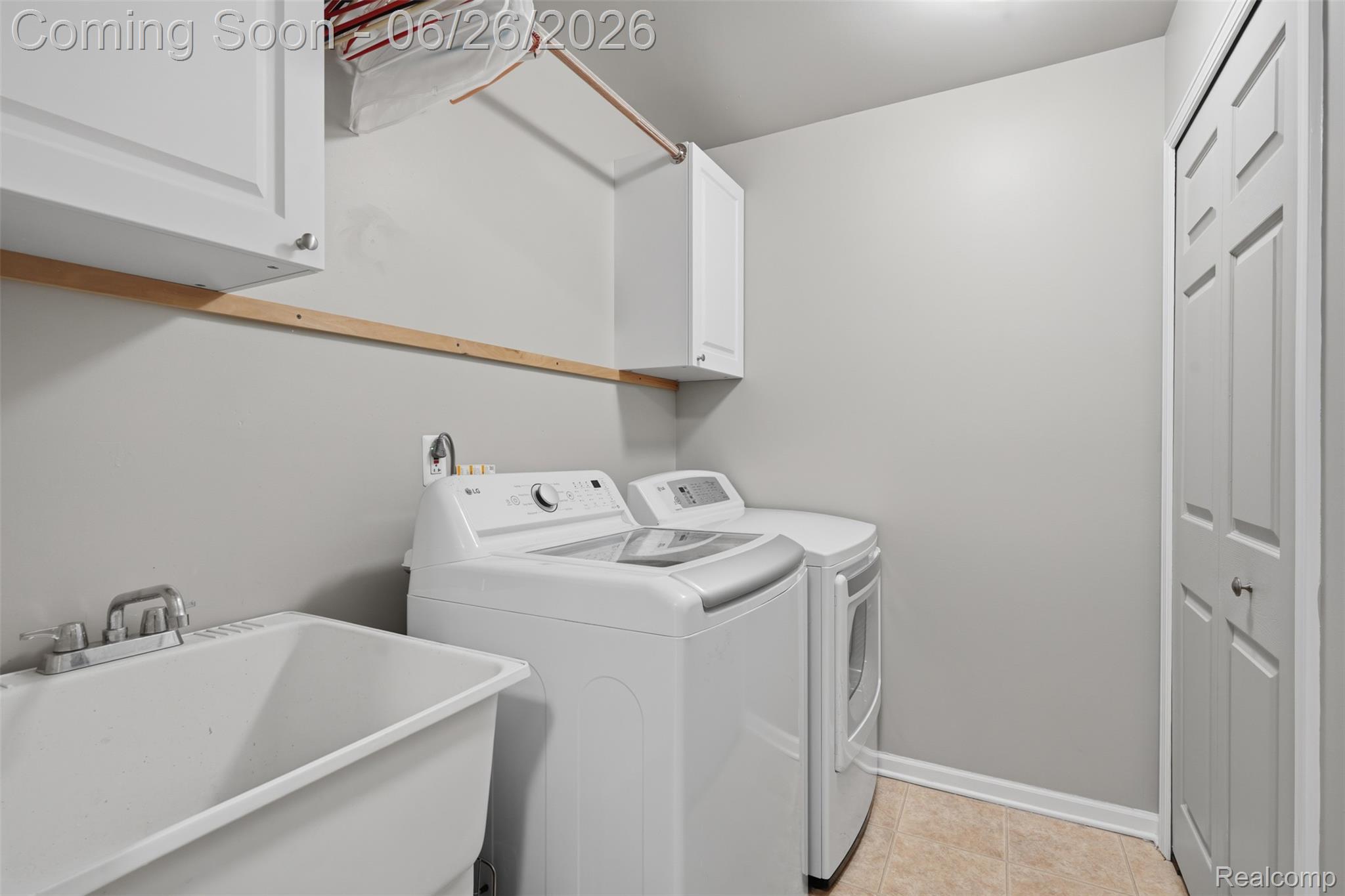 1668 Deepwood Circle Rochester, MI 48307 - Photo 17 of 27 Utility room featuring a built-in laundry sink, white cabinetry, a clothing rod, paneled bifold doors, and neutral-toned flooring