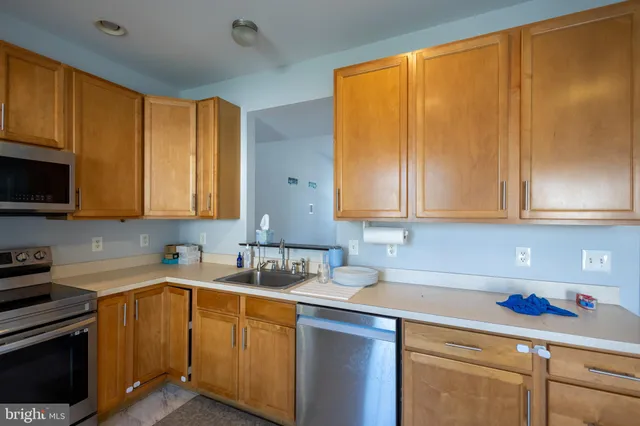 a kitchen with stainless steel appliances wooden cabinets sink and stove top oven
