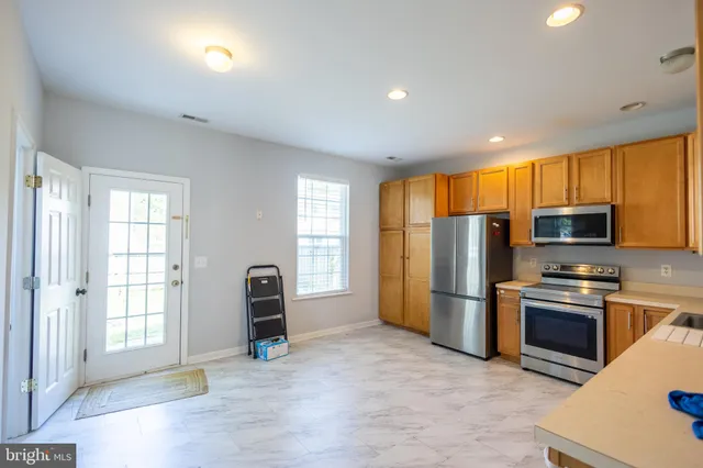 a view of kitchen with stainless steel appliances granite countertop a refrigerator and a stove top oven