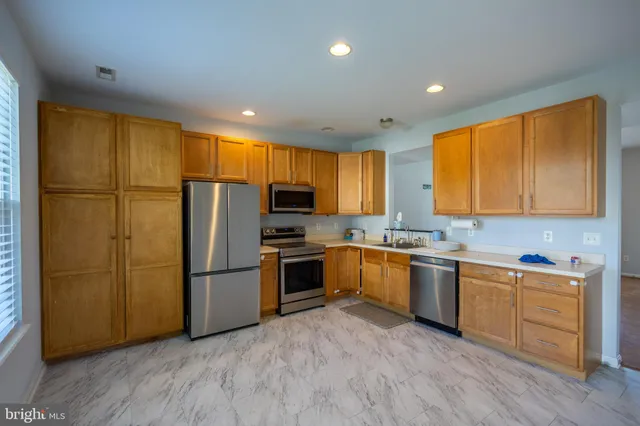 a kitchen with stainless steel appliances granite countertop a refrigerator a sink dishwasher a stove with large countertops and wooden floor