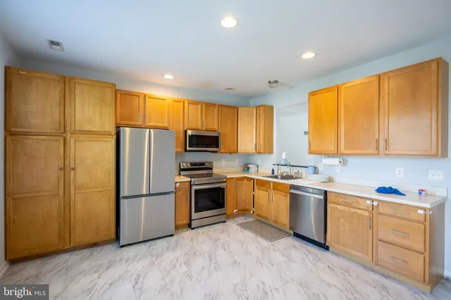 a kitchen with stainless steel appliances granite countertop a refrigerator a stove top oven a sink and dishwasher with wooden floor