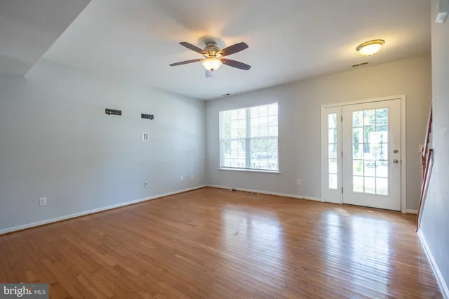 an empty room with wooden floor fan and windows