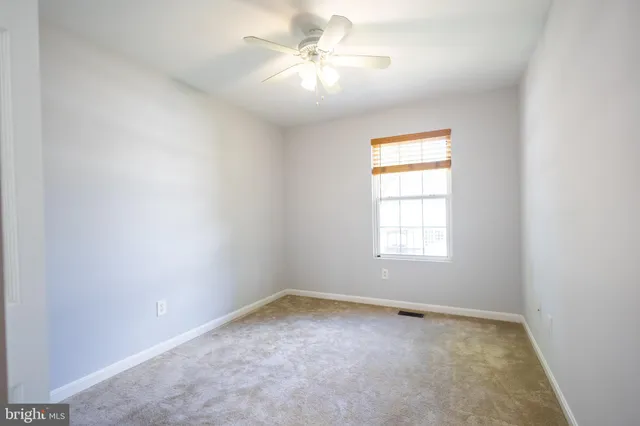 an empty room with a window and a ceiling fan