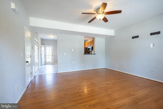 a view of an empty room with window and wooden floor