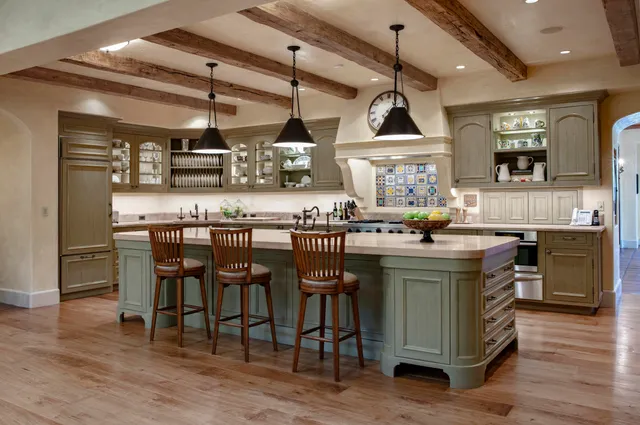 a kitchen with kitchen island stainless steel appliances a table chairs sink and wooden floor