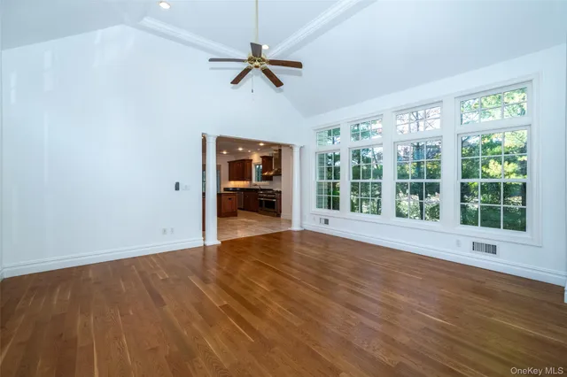 a view of an empty room with a window and wooden floor