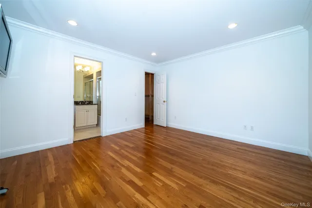 a view of an empty room with wooden floor and closet