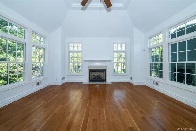 a view of an empty room with window and wooden floor