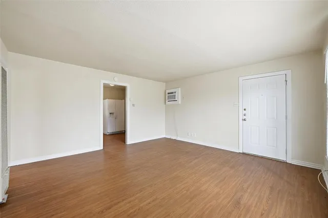 a view of an empty room with wooden floor and closet