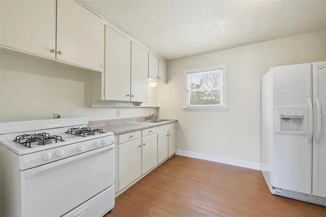 a kitchen with granite countertop white cabinets and white appliances