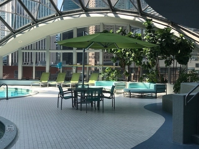 400 East Randolph Street, Unit 1924 Chicago, IL 60601 - Photo 14 of 18 a view of a patio with couches table and chairs under an umbrella with a small yard