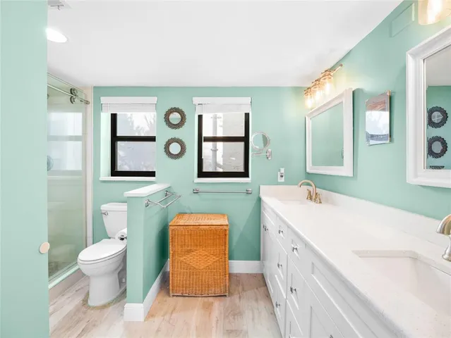 a spacious bathroom with a double vanity sink toilet and mirror