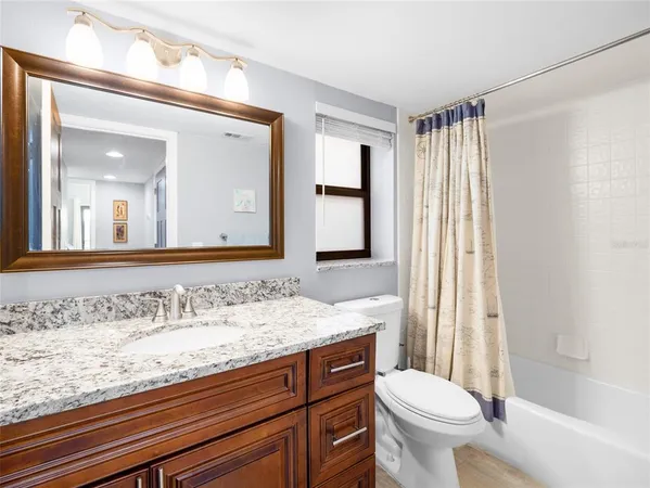 a bathroom with a granite countertop sink toilet and mirror