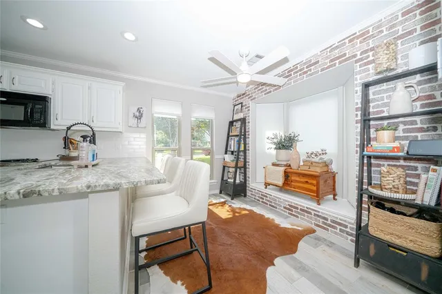 a kitchen with granite countertop a stove a sink a dining table and chairs with wooden floor